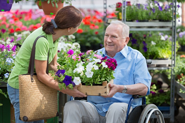 assisted living – caregiver and senior man buy flowers